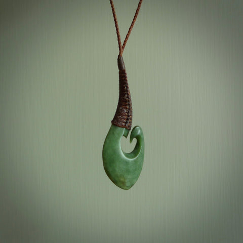 This picture shows a large deep green large jade hook pendant, also called a hei-matau, carved for us in New Zealand jade. The carver is Donna Summers - and this is a beautiful example of his work. The cord is a four-plait, adjustable brown coloured necklace.