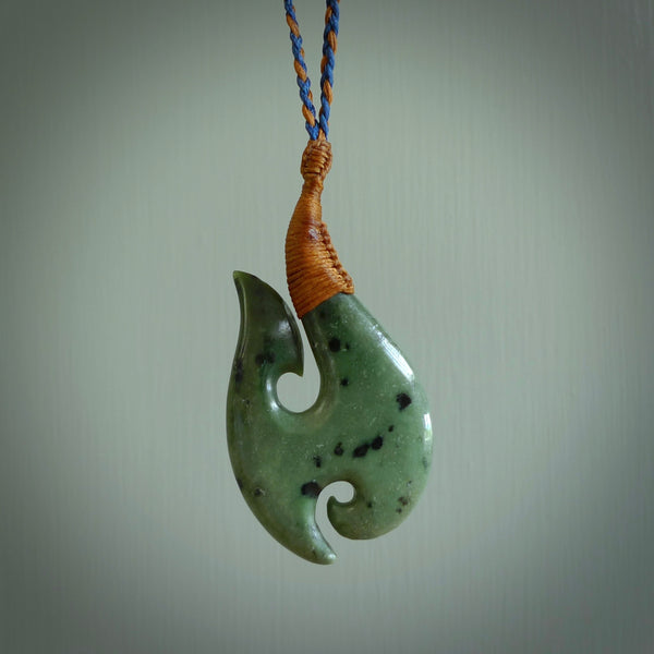 This is a beautiful Kokopu jade hook with a little decorative koru carved into the bottom. It is a chunky piece but beautifully balanced so doesn't look heavy. The cord is a Blue and Brown colour and the binding on the top is Chestnut brown..