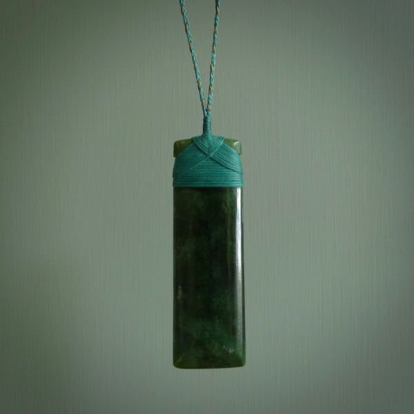 A large and beautiful hand carved toki pendant. This piece is carved from New Zealand jade by NZ Pacific. This is a wonderful large toki bound with a hand-plaited silver and blue cord and a traditional blue lashing. A beautiful, traditional toki for sale online.