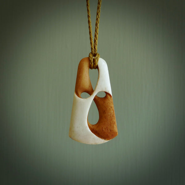 A hand carved bone contemporary, intricate, twist pendant. The cord is a tan colour and is adjustable. A medium sized hand made contemporary necklace by New Zealand artist Tonijae Brockway. Tonijae has stained parts of the bone which really add to the dimension of this pendant. One off work of art to wear.