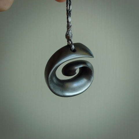 A hand carved medium sized Black Jade Koru necklace. The cord is a black colour and is a fixed length . A medium sized hand made hook necklace by New Zealand artist Kerry Thompson. One off work of art to wear.
