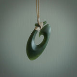 This picture shows a jade hook pendant, also called a hei-matau, carved for us in New Zealand jade. The jade is a wonderful deep mint green pounamu. This is a rare jade loved and valued for its distinctive colour. The carver is Ric Moor - and this is a beautiful example of his work. The cord is a four-plait, adjustable beige coloured necklace.