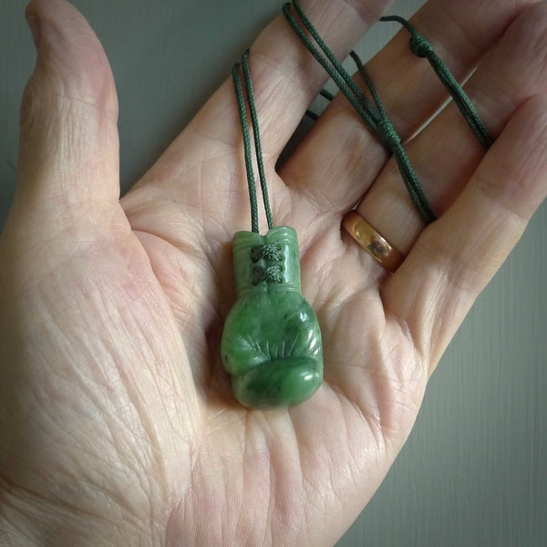 Hand carved boxing glove made from New Zealand Jade. The cord is adjustable so that you can wear this where it suits you best. We have bound these with a Pohutukawa Red cord which contrasts with the green of the jade glove, and reminds of the Everest boxing glove colour. The cost of shipping worldwide is included in the price.