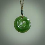 Hand carved New Zealand jade koru pendant. Delivered to you on a hand plaited manuka green cord which is adjustable. Free delivery worldwide.