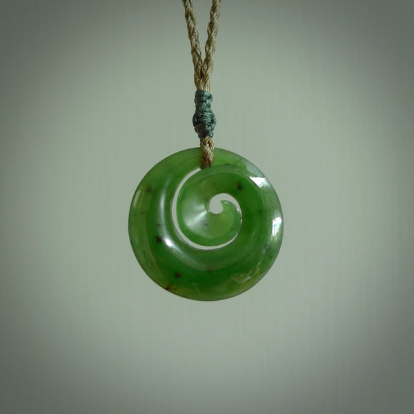 Hand carved New Zealand jade koru pendant. Delivered to you on a hand plaited manuka green cord which is adjustable. Free delivery worldwide.