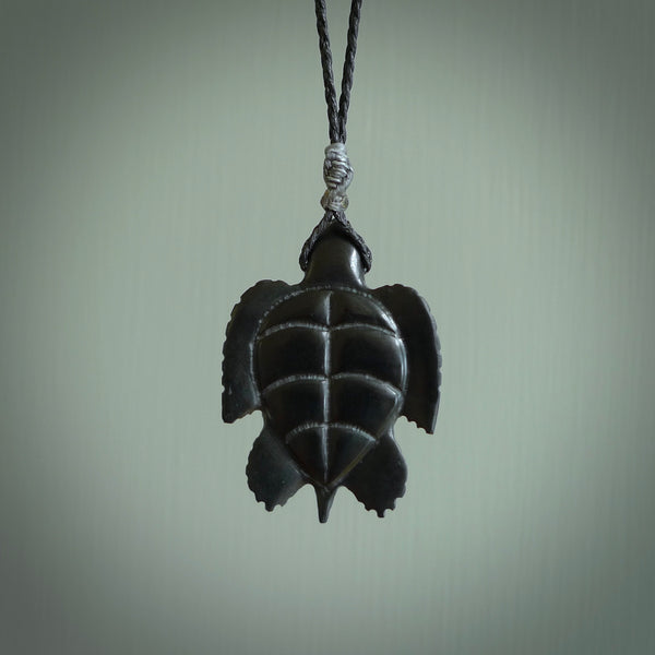 This picture shows a hand carved black jade turtle pendant. It is polished to a soft shine and has quite a lot of detail carved into the jade. The cord is a hand plaited black, waxed polyester. Carved by NZ Pacific.