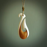 A hand carved bone hook pendant. The cord is a Tan colour and is adjustable. A medium sized hand made hook necklace by New Zealand artist Tonijae Brockway. Tonijae has stained parts of the bone which really add to the dimension of this pendant. One off work of art to wear.