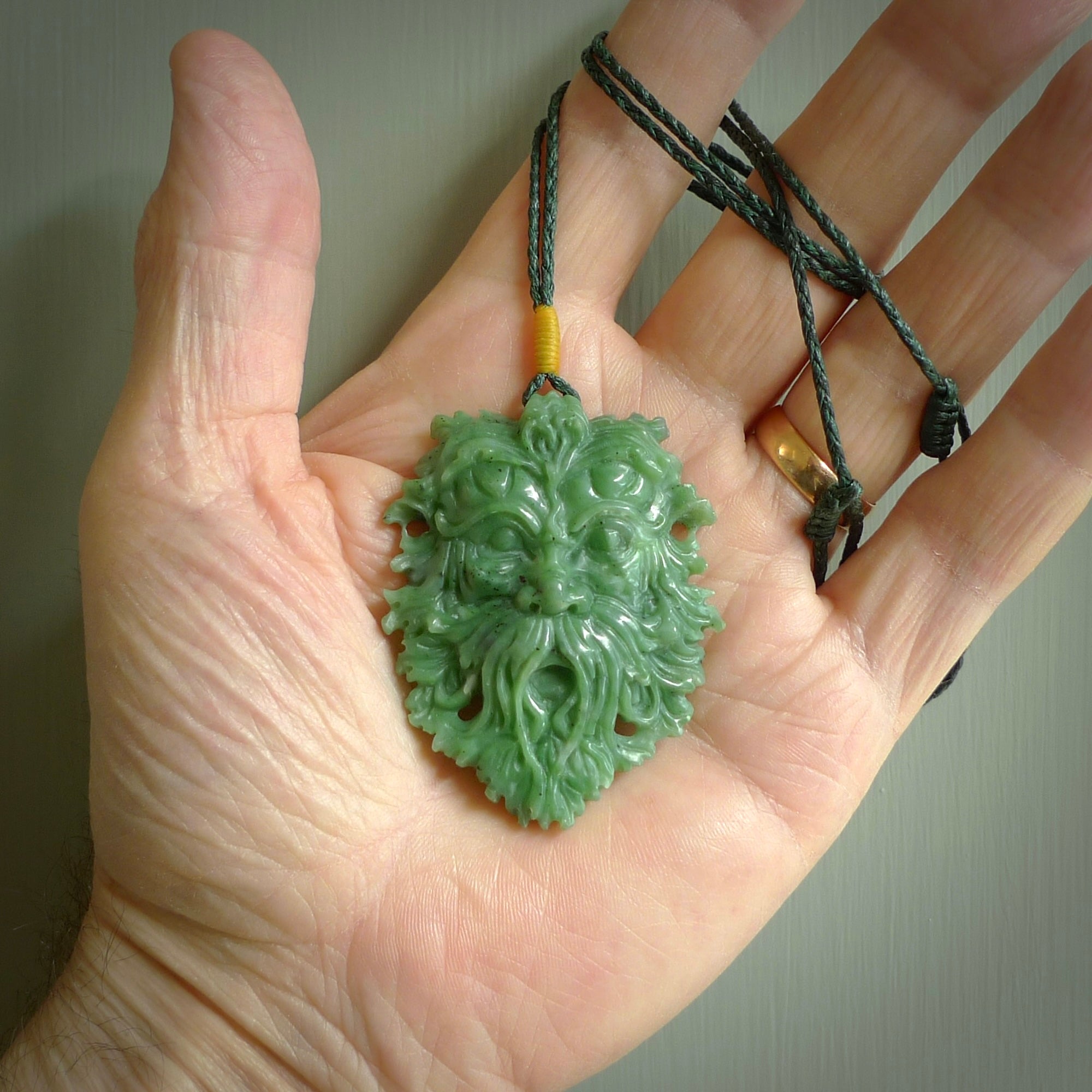 This picture shows a large hand carved forest man face pendant. It is a light green colour which is quite beautiful. Although a large piece, it is a wonderful, delicate piece of jewellery. The cord is hand plaited and adjustable so that you can position the pendant where it suits you best. Delivery is free worldwide.