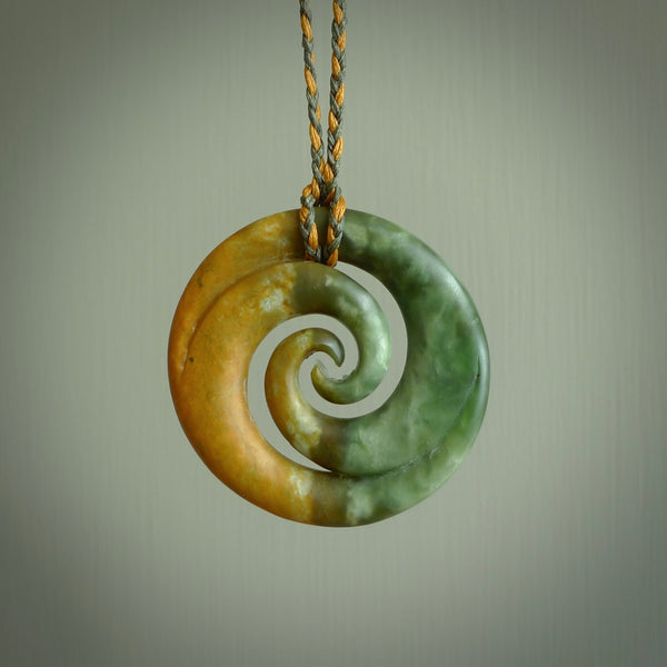 A hand carved koru pendant from New Zealand Jade. The cord is a sage green and harvest gold colour and is length adjustable. A large hand made double Koru necklace by New Zealand artist Kerry Thompson.