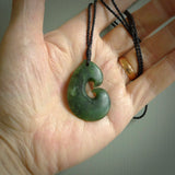 This photo shows a traditional hook pendant. It a a lovely deep green jade. The cord is a four plait black and is adjustable in length. One only, contemporary matau necklace from Jade, by Ric Moor.