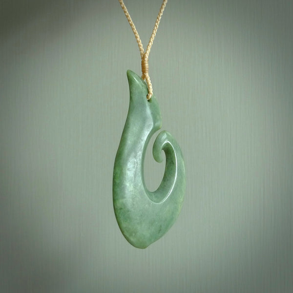 This picture shows a hand carved jade koru pendant. It is a deep green colour and is a wonderful, large sized piece of jewellery. The cord is a four plait beige colour and adjustable so that you can position the pendant where it suits you best. This koru was carved for us by Ric Moor. Delivery is free worldwide.