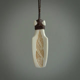 Hand carved engraved bone toki necklace hand made here in New Zealand. One only artistic toki pendant with hand plaited dark brown adjustable cord. Shipped to you with Express Courier. Stand out toki pendant for men and women. Bone Toki with engraved spiral on the back and paua shell insert on the front.