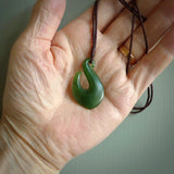 This picture shows a jade hook pendant, also called a hei-matau, carved for us in New Zealand jade. The carver is Ric Moor - and this is a beautiful example of his work. The cord is a four-plait, adjustable brown coloured necklace.