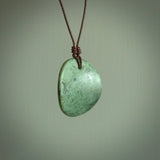 A lovely disc design with cupping on one side and the lightly convex form on the other - a little feature that captures the light and gives the piece a sense of movement and form. Hand made from New Zealand Jade by Ric Moor. Delivered with an adjustable brown cord. 