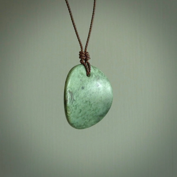 A lovely disc design with cupping on one side and the lightly convex form on the other - a little feature that captures the light and gives the piece a sense of movement and form. Hand made from New Zealand Jade by Ric Moor. Delivered with an adjustable brown cord. 