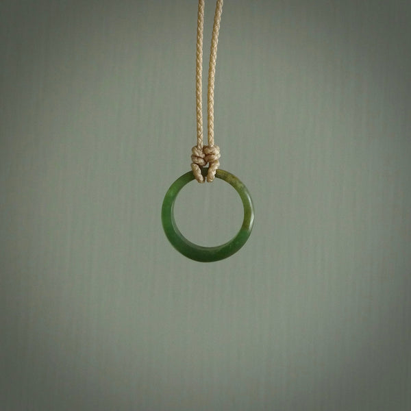 This piece is a oval round, ring pendant. It was carved for us by Ric Moor from a lovely light and milky green piece of New Zealand jade. It is suspended on a beige coloured braided cord that is length adjustable.