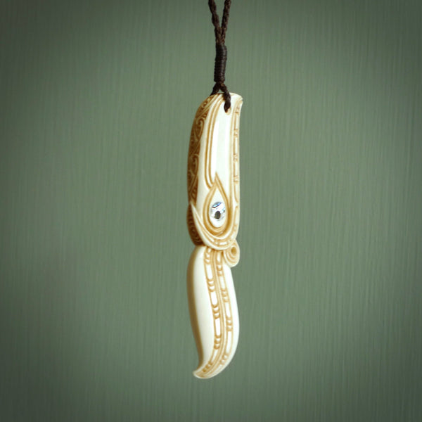 This picture shows a carved hawk in bone. It is a drop shaped pendant. The artist has carved traditional decorative kowhaiwhai designs into the body and these run up the sides of the hawk. These have specific meanings. It is provided with a hand-plaited brown cord that is length adjustable. Shipping is included and we ship worldwide.