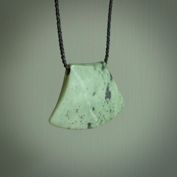 This picture shows a hand carved jade contemporary half-shield pendant. It is a mint green colour. This is a wonderful piece of jewellery. The cord is hand plaited and adjustable so that you can position the pendant where it suits you best. This piece was carved for us by Ric Moor. Delivery is free worldwide.