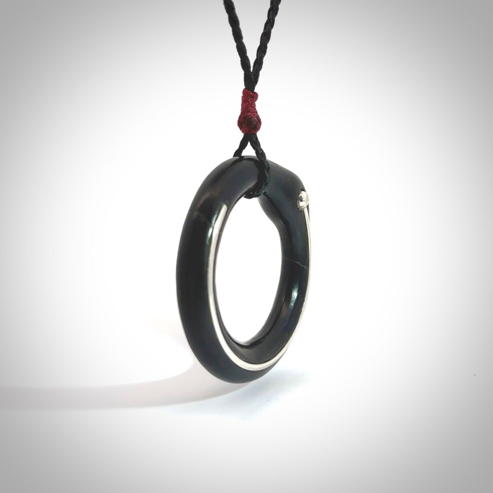 This picture shows a hand carved black jade circle pendant with sterling silver inlay. It is suspended from an adjustable Black cord. Delivery is free worldwide.