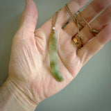 This picture shows a hand carved Spoon River White Jade drop pendant with adjustable cord. The jade is a very light, white green with a shimmer of darker tones in the stone. It is suspended from a tan coloured cord. Delivery is free worldwide.