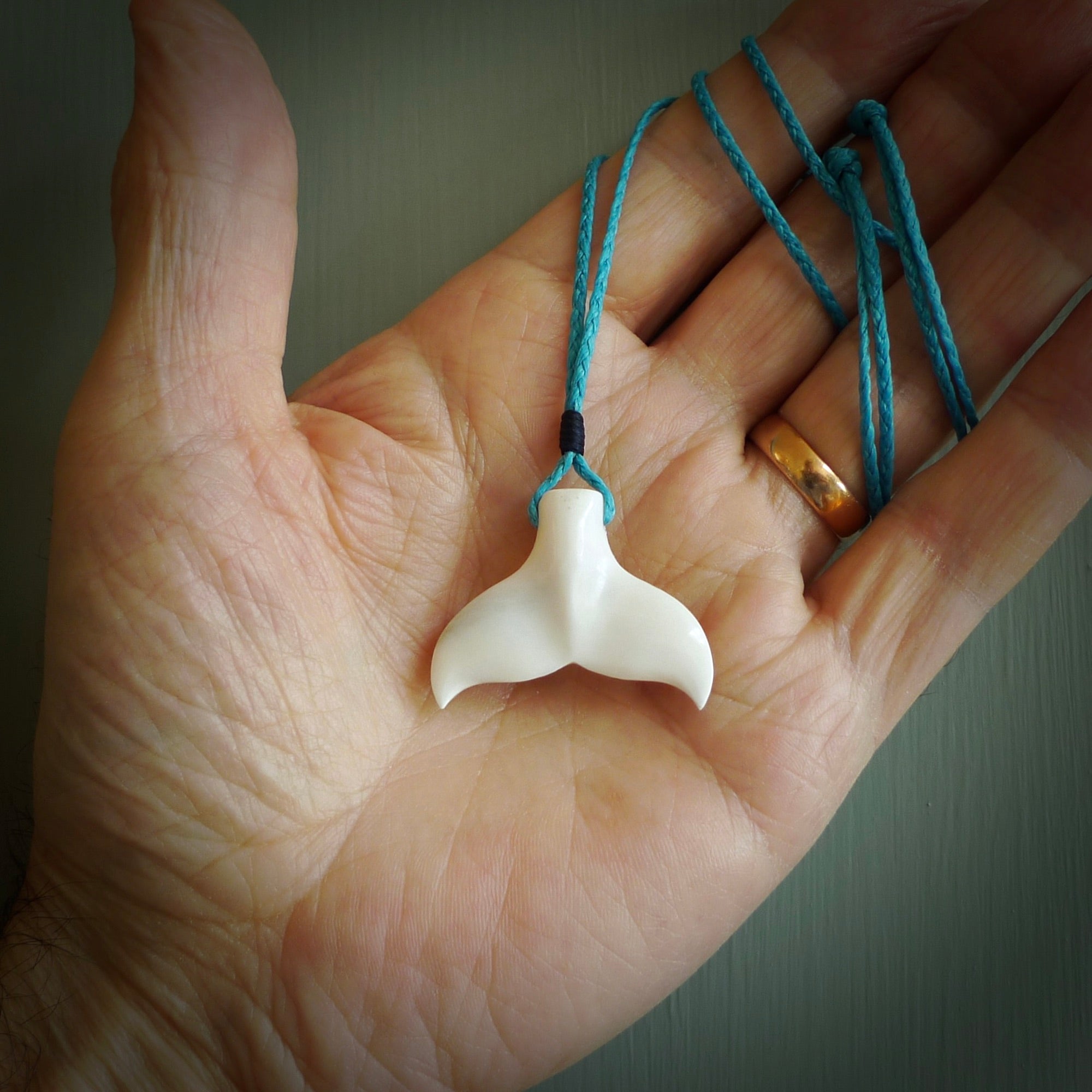 This is a lovely little Dolphin tail pendant. We have handcarved this in a bright, white bone and we make the necklace from a hand-plaited waxed cord. These are original NZ Pacific pendants, handmade from natural materials.