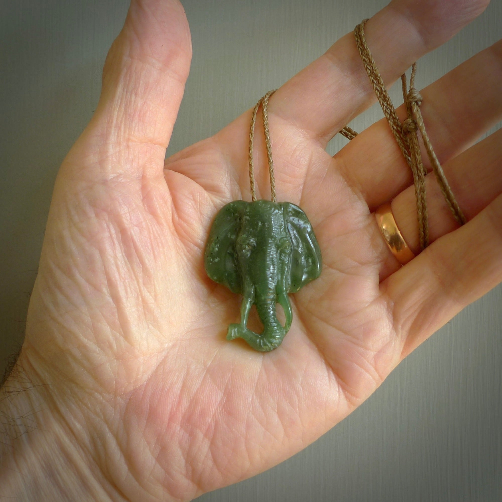This is a hand made elephant pendant. Carved in a beautiful darker green piece of Aceh jade. The cord is hand-plaited in an Oat colour and is length adjustable. Provided in a woven kete pouch and delivered with express courier.