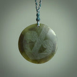 Hand carved jade disc pendant. One side has a double koru etched into the face. This is a subtle and beautiful design. The other side is plain. The cord is a tan colour and is adjustable. The piece was carved for NZ Pacific by Rueben Tipene.