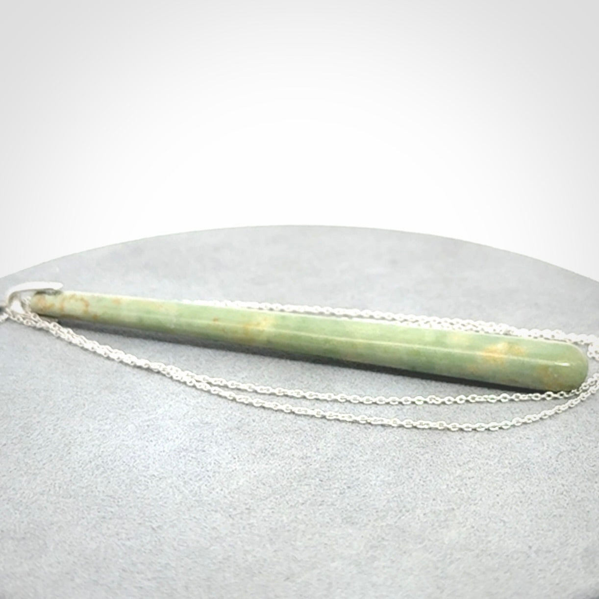 A hand carved New Zealand Jade Drop pendant with sterling silver clasp and chain.