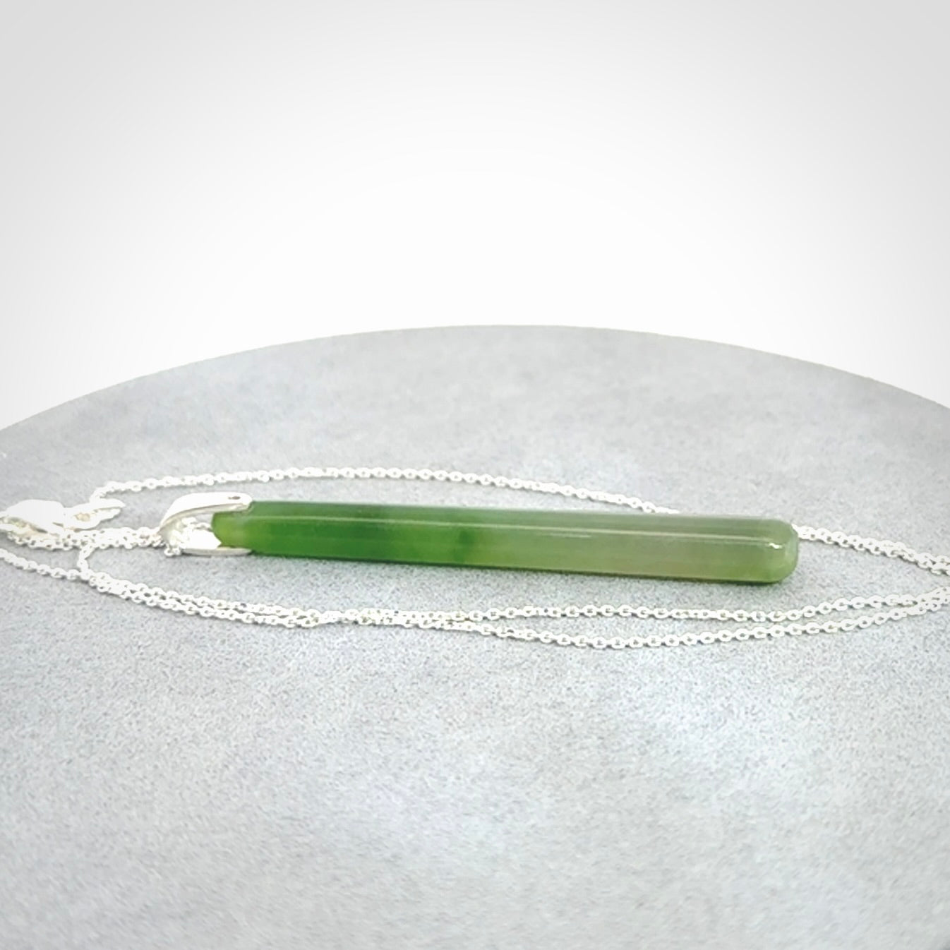 A hand carved New Zealand Jade Drop pendant with sterling silver clasp and chain.