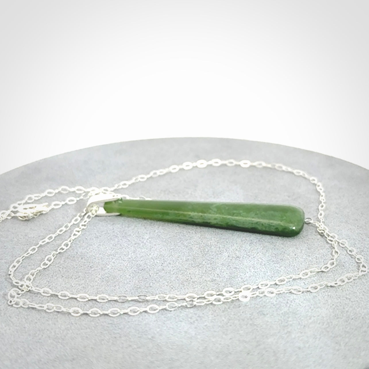 A hand carved New Zealand Jade Drop pendant with sterling silver clasp and chain.