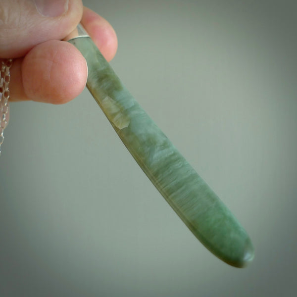 This picture shows a hand carved Inanga Pounamu, jade drop pendant with sterling silver cap and chain. The jade is a very dark green with a shimmer of light blue tones in the stone. It is suspended from a sterling silver clasp and we supply a sterling silver chain. Delivery is free worldwide.