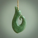 This picture shows a hand carved jade koru pendant. It is a deep green colour and is a wonderful, large sized piece of jewellery. The cord is a four plait beige colour and adjustable so that you can position the pendant where it suits you best. This koru was carved for us by Ric Moor. Delivery is free worldwide.