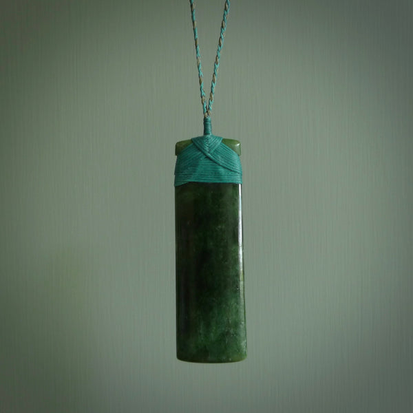 A large and beautiful hand carved toki pendant. This piece is carved from New Zealand jade by NZ Pacific. This is a wonderful large toki bound with a hand-plaited silver and blue cord and a traditional blue lashing. A beautiful, traditional toki for sale online.