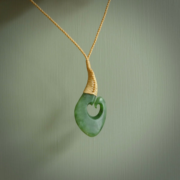 Hand carved jade matau or hook pendant. Carved by New Zealand artist Donna Summers. This matau, is carved from a very striking New Zealand jade. It is both intricate and simple in design - it has hidden folds and smooth curves. A piece to be worn or displayed - the carving and the jade are both magnificent. Hand made by Donna Summers.