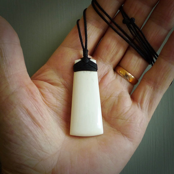A hand carved bone toki pendant. The cord and binding is black and the cord is adjustable. Medium hand made toki necklaces by New Zealand artist Kerry Thompson. One off work of art to wear.