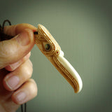 This picture shows a carved kāhu, hawk in bone. It is a drop shaped pendant. The artist has carved traditional decorative kowhaiwhai designs into the body and these run up the sides of the hawk. These have specific meanings. It is provided with a hand-plaited brown cord that is length adjustable. Shipping is included and we ship worldwide.