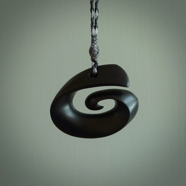 A hand carved medium sized Black Jade Koru necklace. The cord is a black colour and is a fixed length . A medium sized hand made hook necklace by New Zealand artist Kerry Thompson. One off work of art to wear.