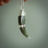 This picture shows a jade and sterling silver talon pendant with an adjustable cord. The pendant looks a little like a fang. A hand made unique and contemporary necklace hand carved here in New Zealand.