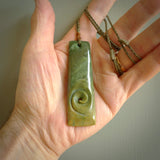 A hand carved toki pendant with a koru carved into the front face. This is a piece of genuine jade jewellery, hand carved by Ross Crump. He has used rare New Zealand flower jade and has utilised his experience and carving skill to highlight the natural beauty of the stone. Delivered worldwide, postage is included in the price.