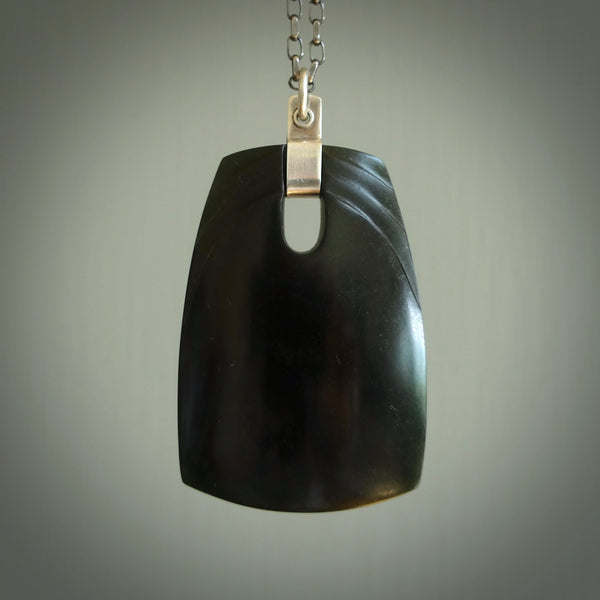 This photo shows a square drop pendant suspended from a silver clasp and silver chain. The jade is a deep, dark New Zealand jade with a subtle dual wave design on the front. A lovely soft New Zealand jade pendant carved for us by Josey Coyle.