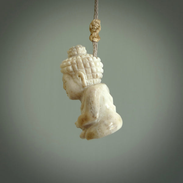 This photo shows a praying Buddha pendant hand carved in deer antler and woolly mammoth tusk. It is provided with a plaited cord necklace which is length adjustable. Your choice of either material. Delivered in a woven kete pouch. 