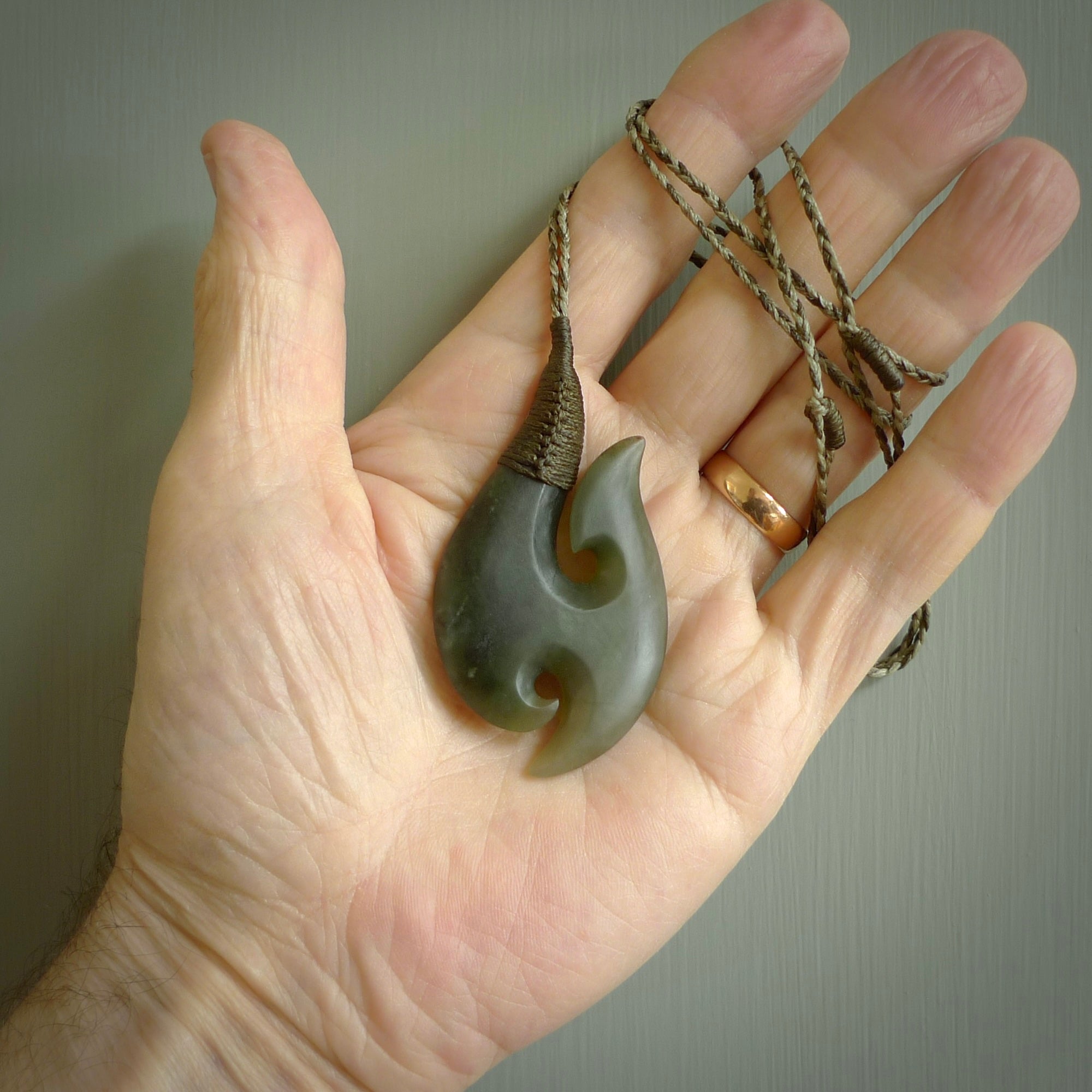 This is a beautiful flower jade hook with a little decorative koru carved into the bottom. It is a chunky piece but beautifully balanced so doesn't look heavy. The cord is a mushroom/khaki colour and the binding on the top is a Chestnut colour.