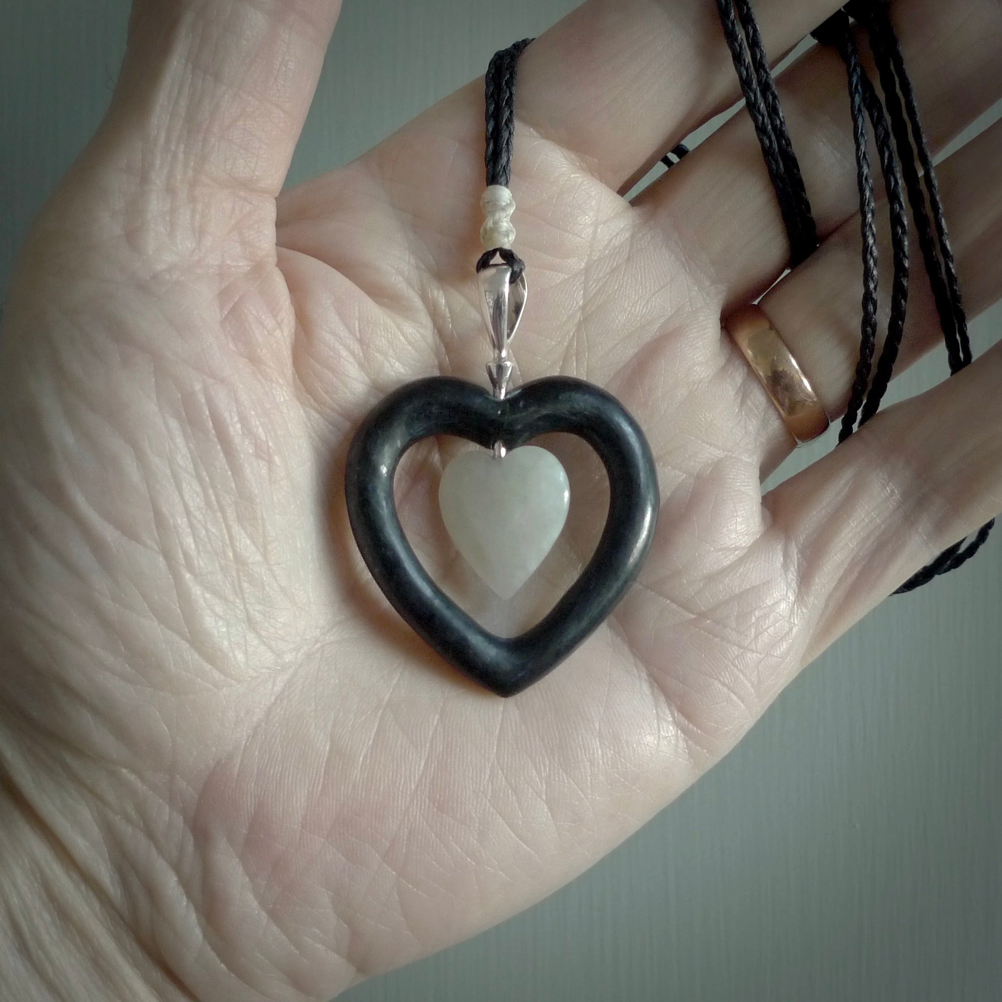 Black Jade Heart pendant with Jadeite heart centre. Hand carved for NZ Pacific. Handmade jewellery for sale online. The cord is a 3-braid plait in black and is adjustable. Double heart necklace for men and women. Heart necklace hand made from black jade stone and Jadeite.