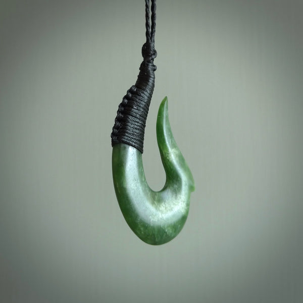 This photo shows a greenstone hook, or matau, pendant. It is a beautiful green kahurangi jade. The cord is plaited and the length can be adjusted.
