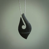 A hand carved large New Zealand Tangiwai Hook, Matau, necklace. The cord is a cosmos and blue moon grey colour and is length adjustable. A large sized hand made hook necklace by New Zealand artist Rueben Tipene. One off work of art to wear.