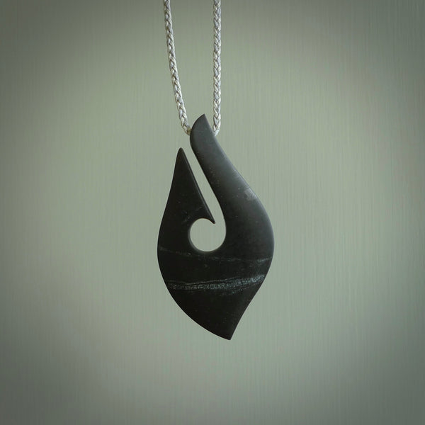 A hand carved large New Zealand Tangiwai Hook, Matau, necklace. The cord is a cosmos and blue moon grey colour and is length adjustable. A large sized hand made hook necklace by New Zealand artist Rueben Tipene. One off work of art to wear.