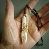This picture shows a carved hawk in bone. It is a drop shaped pendant. The artist has carved traditional decorative kowhaiwhai designs into the body and these run up the sides of the hawk. These have specific meanings. It is provided with a hand-plaited brown cord that is length adjustable. Shipping is included and we ship worldwide.