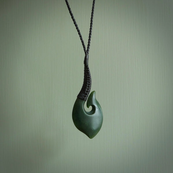 This picture shows a large deep green large jade hook pendant, also called a hei-matau, carved for us in New Zealand jade. The carver is Donna Summers - and this is a beautiful example of his work. The cord is a four-plait, adjustable black coloured necklace.