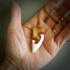 A hand carved bone toki with double koru, intricate pendant. The cord is a tan colour and is adjustable. A medium sized hand made toki with koru necklace by New Zealand artist Tonijae Brockway. Tonijae has stained parts of the bone which really add to the dimension of this pendant. One off work of art to wear.