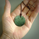 A lovely disc design with cupping on one side and the lightly convex form on the other - a little feature that captures the light and gives the piece a sense of movement and form. Hand made from New Zealand Jade by Ric Moor. Delivered with an adjustable brown cord. 
